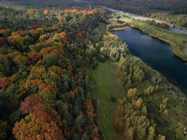 背景に高速道路がある秋の森の中の湖の空中撮影 — ストック写真