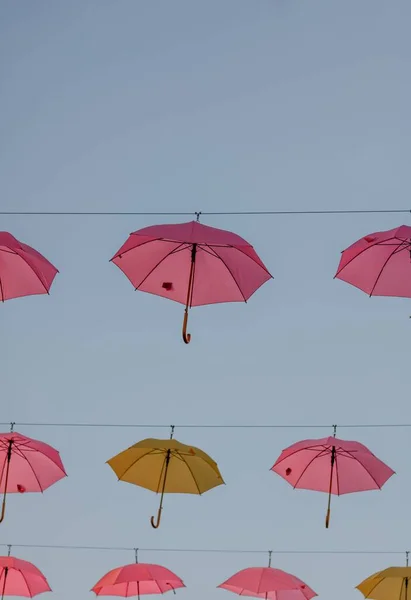 Vertikal Bild Rosa Och Gula Paraplyer Hängande Från Trådar Mot — Stockfoto