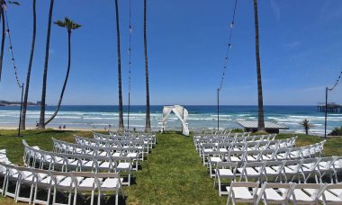 Yeşil çimenlerin üzerinde beyaz sandalyelerin manzarası sahilde bir düğün törenine hazır.