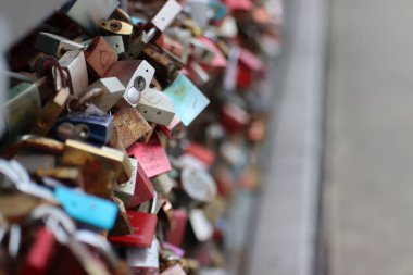 Köprünün korkuluklarında renkli asma kilitlerin seçici odak noktası