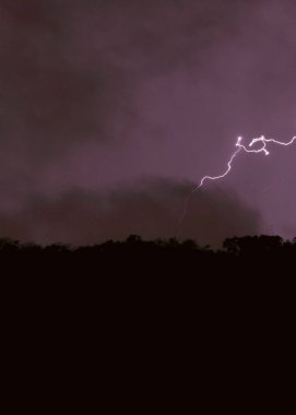 Mor gökyüzündeki şimşeğin dikey görüntüsü.