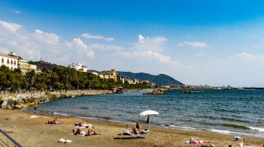 İtalya 'nın Salerno şehrinde güneşli bir yaz gününde, açık mavi denizin kenarında dinlenen insanların olduğu güzel bir sahil manzarası.