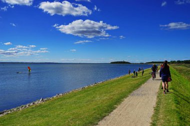 Solunda Baltık Denizi olan bir yol ve Almanya Fehmarn 'da bisiklet süren insanlar.