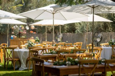 Güneşli bir günde sokakta küçük çiçeklerle süslenmiş ahşap bir festival masası.