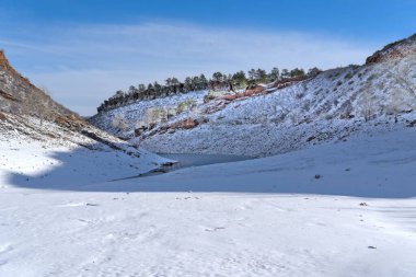 Arka planda kışın karla kaplı kayalık dağlar olan bir tarla.