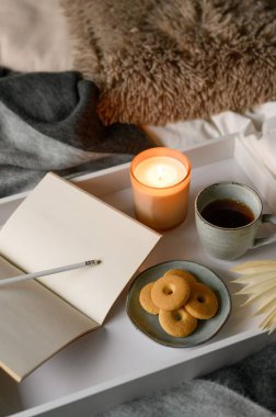 Bir fincan kahveyle, mumla, kurabiyelerle, defterle, kalemle rahat bir sonbahar kompozisyonu.