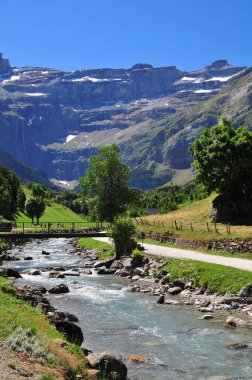 Dağların arka planında küçük bir köprüsü olan nehir. Gavarnie Sirki, Fransa.
