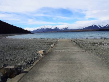 Yeni Zelanda 'daki Tekapo gölü ve dağ manzarasına giden bir yol.