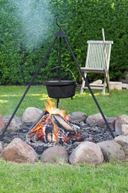 Parktaki bir kovanın altında yanan tahta parçalarının dikey çekimi.