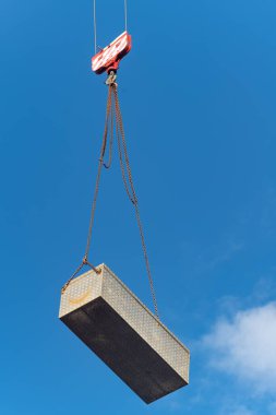 Mavi gökyüzünde ağır yük taşıyan bir vincin dikey alçak açılı görüntüsü.