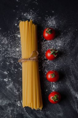 Etrafı kirazlı domateslerle çevrili bir restoranda süslü bir masada çiğ makarnanın yakın çekimi.