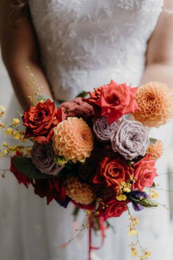 Elinde bir buket çiçek tutan bir kadının dikey görüntüsü.