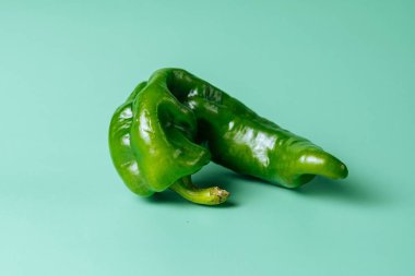 Mavi arka planda izole edilmiş yeşil biberin yakın çekimi.