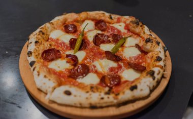 Ahşap masadaki sosis ve peynirli yeni pişmiş pizzanın üst görüntüsü.