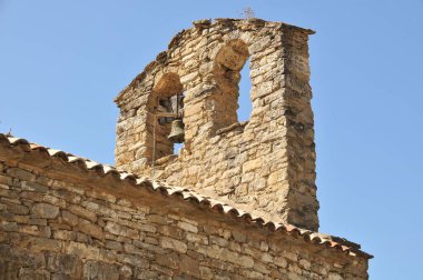 Bulutsuz mavi gökyüzüne karşı eski bir taş bina çanının alçak açılı görüntüsü.