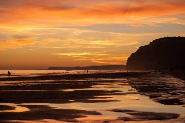 Lagos sahilinin üzerinde turuncu bir günbatımı manzarası.