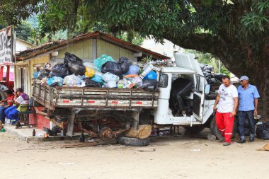 Brezilya 'daki Ilha Bella' da çöp dolu bozuk bir kamyonun yanında duran iki adam.