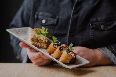 Bulaşık beyazı bir plaka ve bulanık arka plan tutan bir adam.