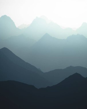 Güneş ışığında dağların mavimsi siluetlerinin dikey bir görüntüsü..