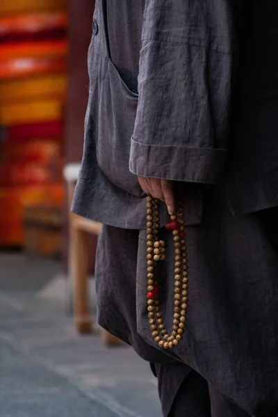 一个身穿灰色衣服拿着念珠的僧人的垂直射击 — 图库照片
