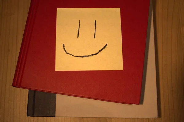 快乐的笑脸贴在书上 — 图库照片