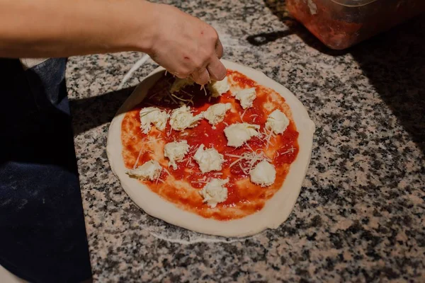 在厨房的披萨 披萨烹调过程中 女性将奶酪放在披萨上的特写镜头 — 图库照片