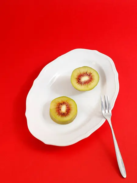 Tiro Vertical Kiwi Frutas Cortadas Meio Placa Branca Fundo Vermelho — Fotografia de Stock