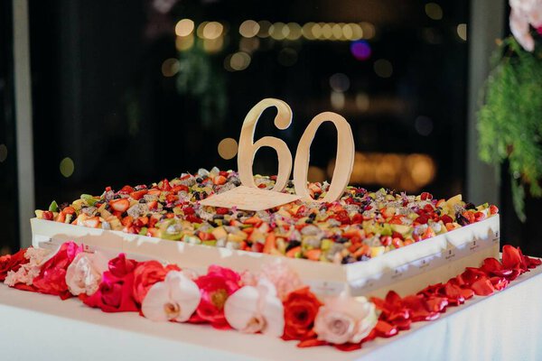 A closeup shot of a large square 60th birthday cake with flowers