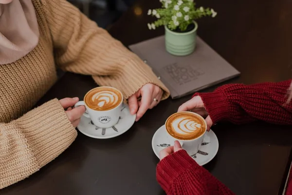 Två Flickor Njuter Cappuccino Kaffe Bar Med Blomkrukor Dekorera Bordet — Stockfoto