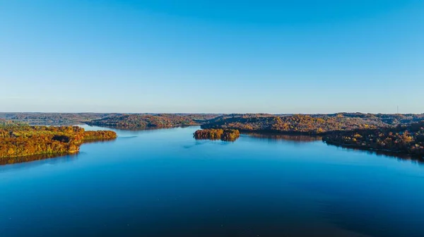 青い雲のない空の下 秋に木々に覆われた丘に囲まれたオハイオ湖の空の景色 — ストック写真