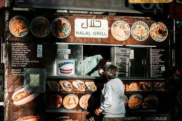 Stock image A person buying food from a halal grill kiosk in New York City