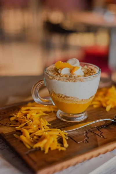 Pionowe Zbliżenie Szklanki Deseru Jogurtem Mango Drewnianej Desce Plastrami Mango — Zdjęcie stockowe