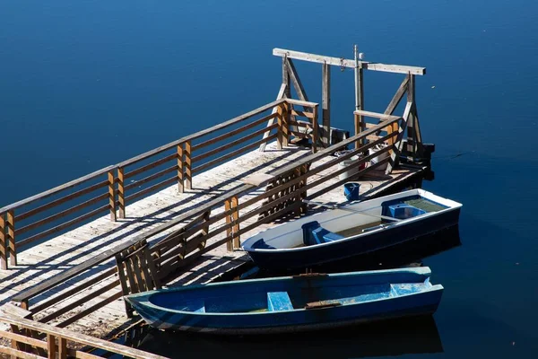 澄んだ青い水の上に木製のポンツーンに結ばれた2隻のボート — ストック写真