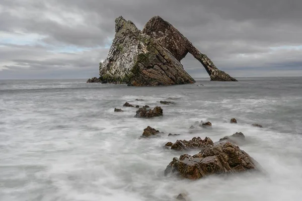 ビーチの海岸に位置する岩を打つ海の波の長い露出ショット — ストック写真
