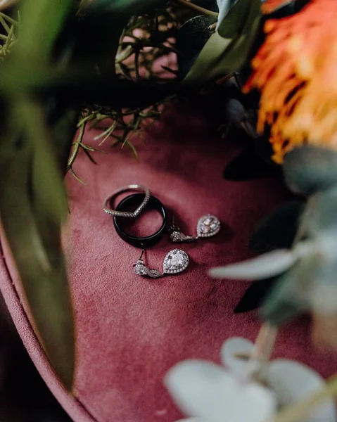 赤い表面に婚約指輪とシルバーイヤリングの垂直クローズアップショット — ストック写真