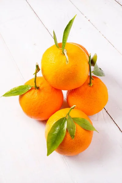 鮮やかなオレンジ色の柑橘系の背景に白い木製のテーブルの上に甘いジューシーなみかん — ストック写真