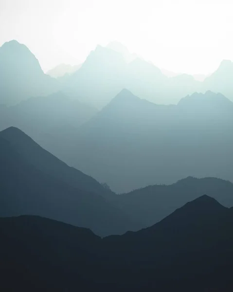 Tiro Vertical Das Silhuetas Azuladas Montanhas Luz Sol — Fotografia de Stock
