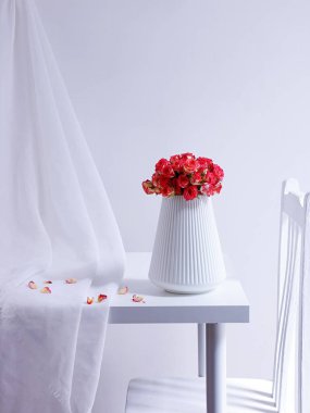 Minimalist beyaz bir masada, beyaz bir vazoda pembe bir gül buketinin güzel manzarası.
