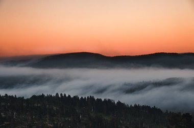 Kuzey Norveç 'te gün batımında siste gizlenmiş dağlı doğal bir manzara.
