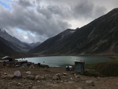 Bulutlu gökyüzünün altındaki tepelerle çevrili kayalık bir sahilin güzel manzarası.