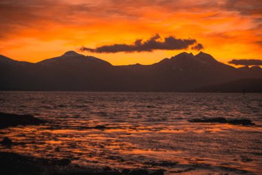 Günbatımında büyüleyici bir deniz manzarası. Arka planda dağların silueti.