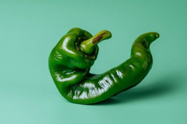 Mavi arka planda izole edilmiş yeşil biberin yakın çekimi.