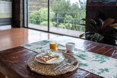 Kafede, ahşap masada, waffle, meyve suyu ve kahve ile rahat bir köy kahvaltısı.