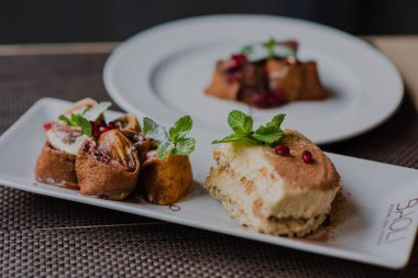 Beyaz tabaklarda iki çöl, karanlık ve bulanık arka plana karşı bir masada.