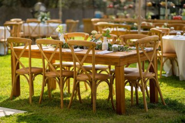 Güneşli bir günde sokakta küçük çiçeklerle süslenmiş ahşap bir festival masası.