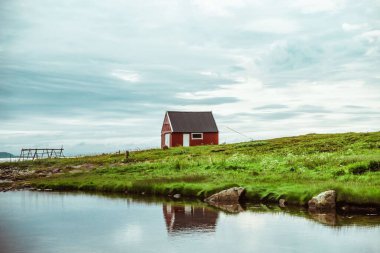 Norveç 'teki çimenli bir gölün kıyısındaki ahşap bir evden büyüleyici bir görüntü.