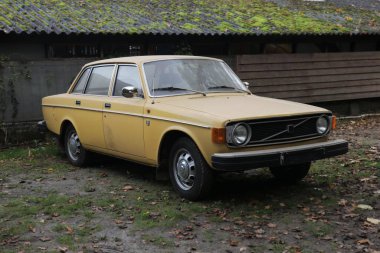 Dışarıda duran eski, sarı bir araba.