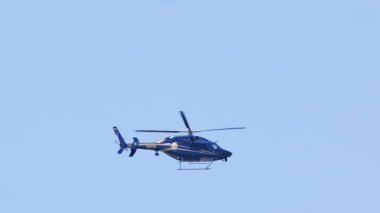 Mavi gökyüzünde uçan bir Delaware Eyalet Polisi helikopteri.