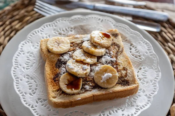 木のテーブルの上でトーストに新鮮なカットバナナ チョコレート 砂糖の粉の水平クローズアップ — ストック写真
