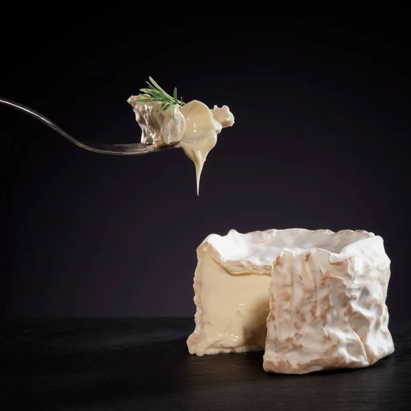 暗い背景にローズマリーとフォークで調理されたカマンベールチーズのクローズアップ — ストック写真